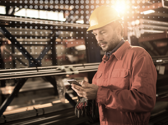 Industrial worker in a hard hat looking at a smartphone